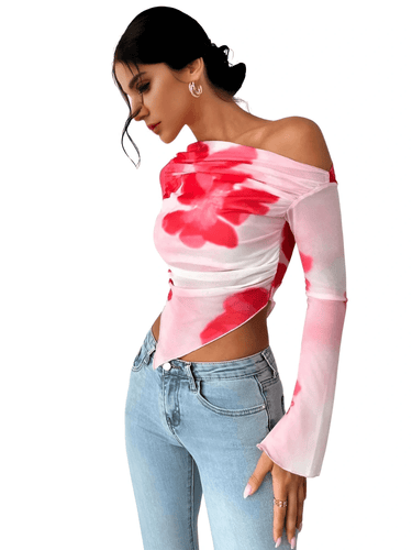 Woman wearing a pink and red floral off-shoulder top with light blue jeans on a white background